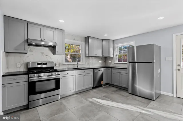 a kitchen with stainless steel appliances granite countertop a stove a refrigerator and a sink