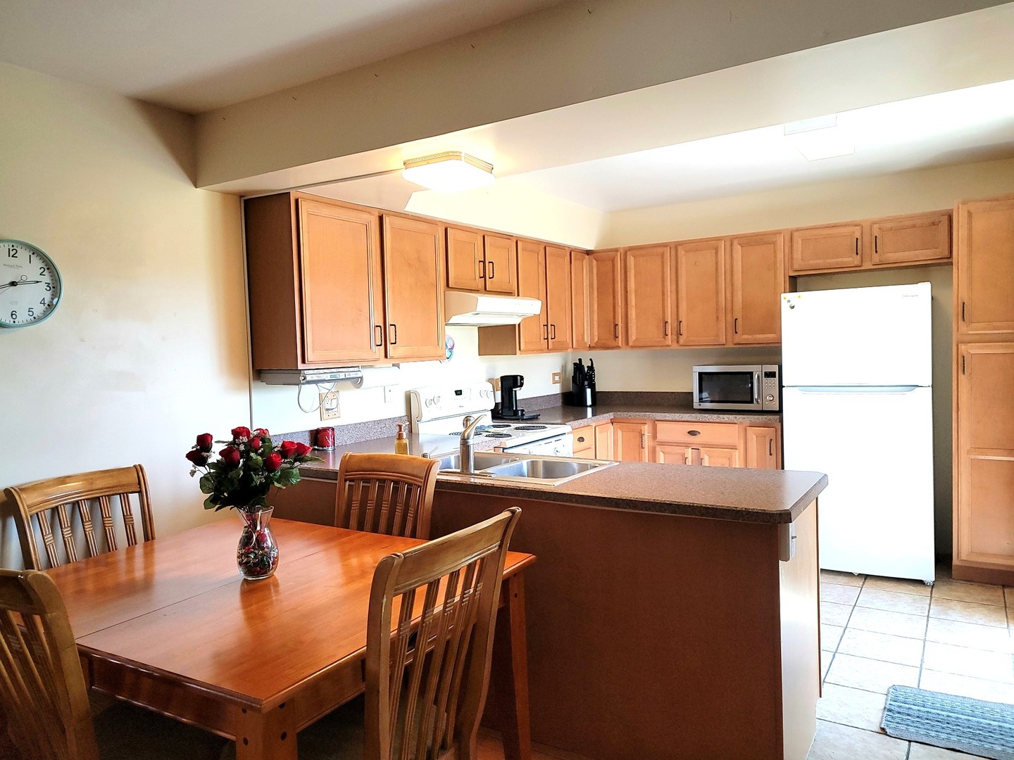 561 Dunham Road Gurnee, IL 60031 - Photo 8 of 30 a kitchen with a refrigerator a sink dishwasher and a dining table with wooden cabinet