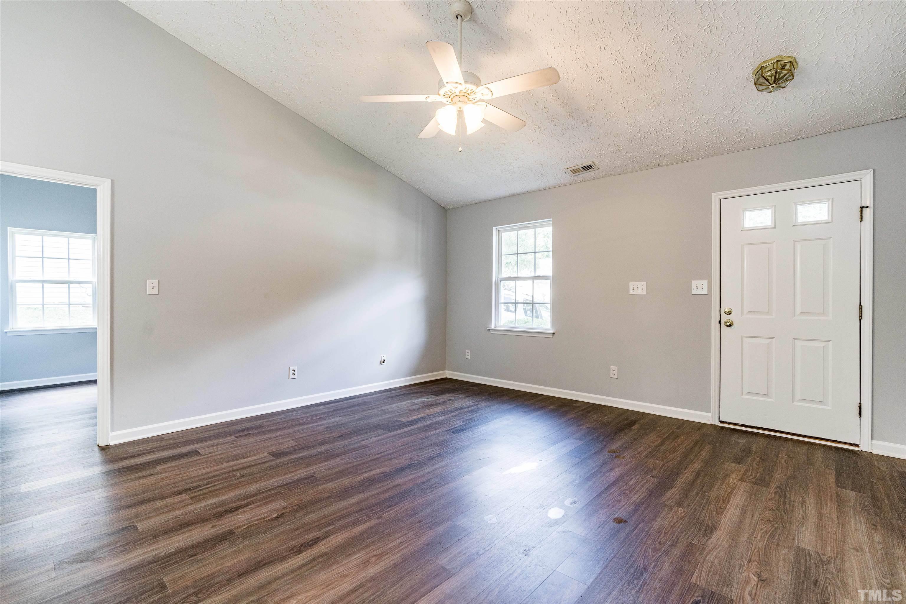 3208 Slippery Elm Drive Raleigh, NC 27610 - Photo 3 of 24 an empty room with wooden floor chandelier fan and windows