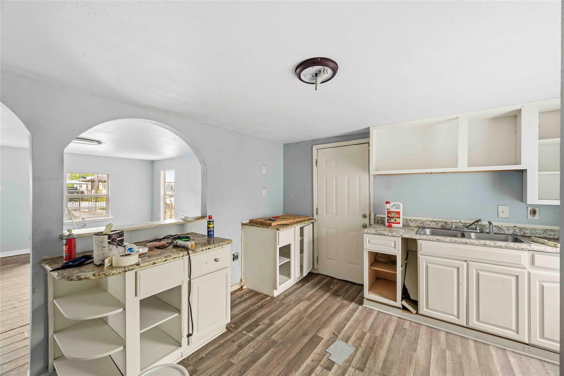 5513 Makeig Street Houston, TX 77026 - Photo 20 of 33 A bright kitchen with natural light, ample cabinetry, and an open layout with an arched entryway, creating a functional space with potential for updates and personalization.