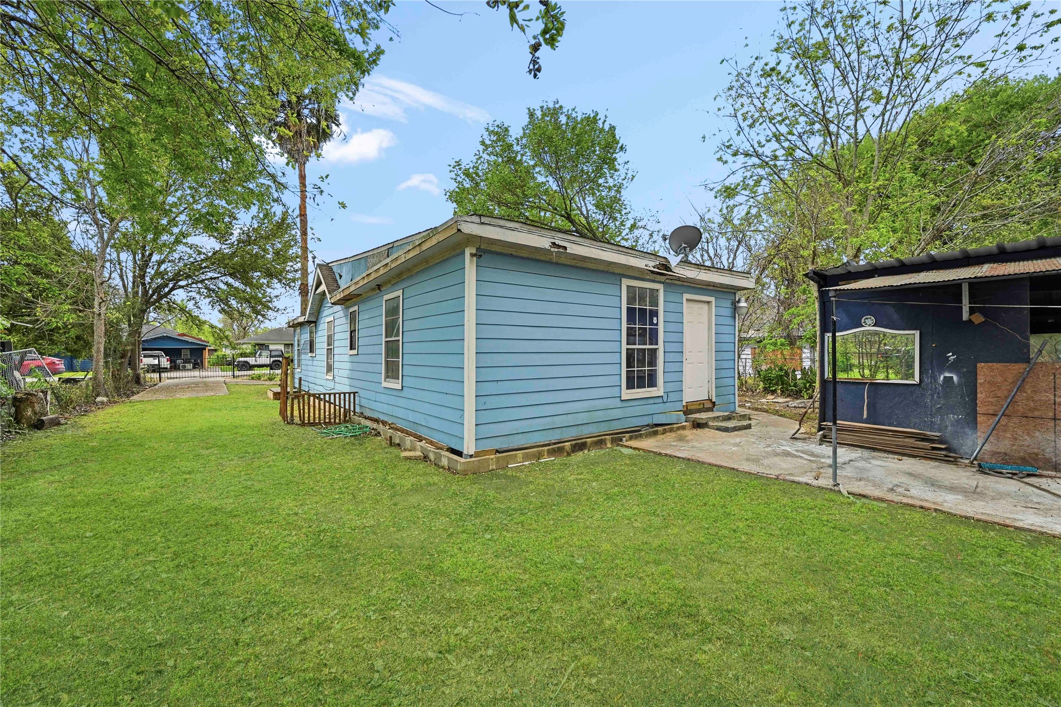 5513 Makeig Street Houston, TX 77026 - Photo 27 of 33 Charming home with a spacious backyard surrounded by mature trees, featuring a side entrance and a patio area perfect for enjoying the outdoors.