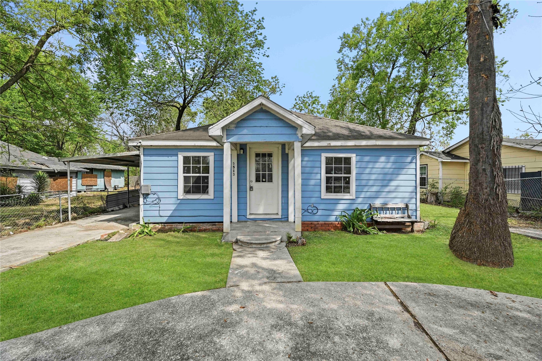 5513 Makeig Street Houston, TX 77026 - Photo 32 of 33 Charming home with a welcoming front porch, surrounded by mature trees and a peaceful setting. The property includes a maintained lawn, paved driveway, and carport for added convenience.