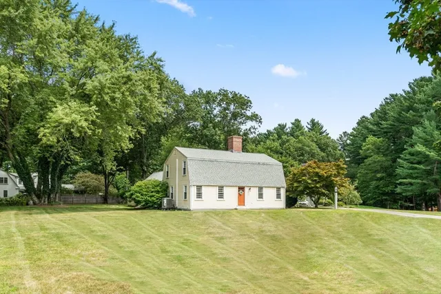 a front view of a house with a yard and trees