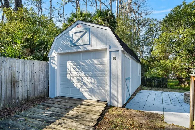 a backyard of a house with table and chairs plants and large tree