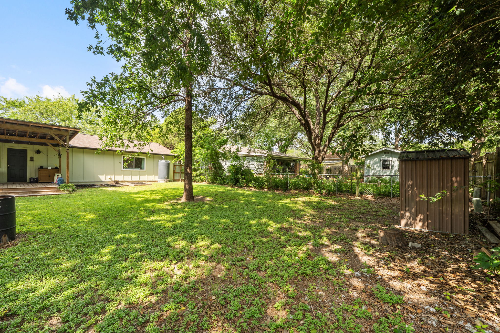 705 Dulwich Street Austin, TX 78748 - Photo 31 of 36 A verdant backyard retreat featuring mature trees, a storage shed, and a charming covered patio.