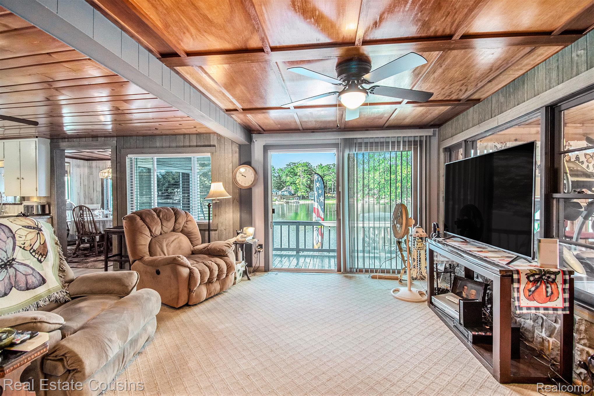 1734 Forest Road Harrison, MI 48625 - Photo 5 of 31 Living room featuring healthy amount of natural light, wood walls, a ceiling fan, carpet, and wooden ceiling