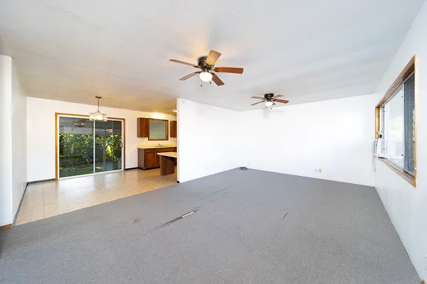 an empty room with windows and chandelier fan