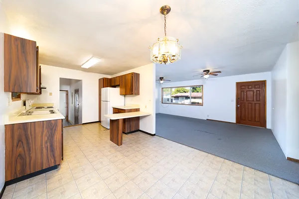 a view of livingroom with kitchen island stainless steel appliances kitchen island granite countertop furniture and a chandelier