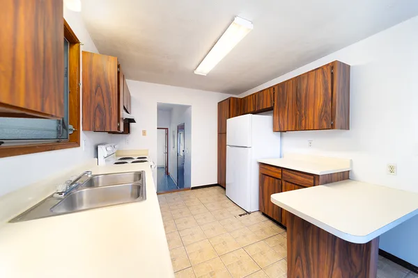 a kitchen with stainless steel appliances a stove a sink a refrigerator with wooden cabinets
