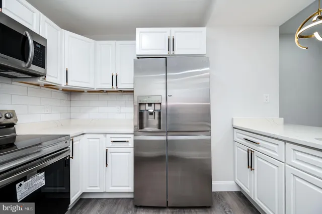a kitchen with kitchen island white cabinets and refrigerator