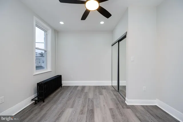 an empty room with wooden floor chandelier fan and windows