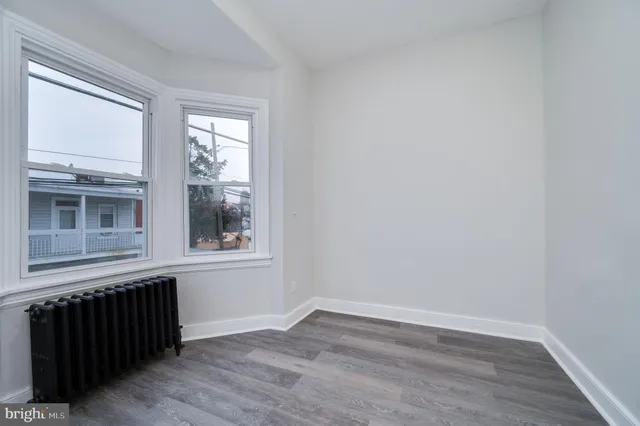 a view of an empty room with wooden floor and windows