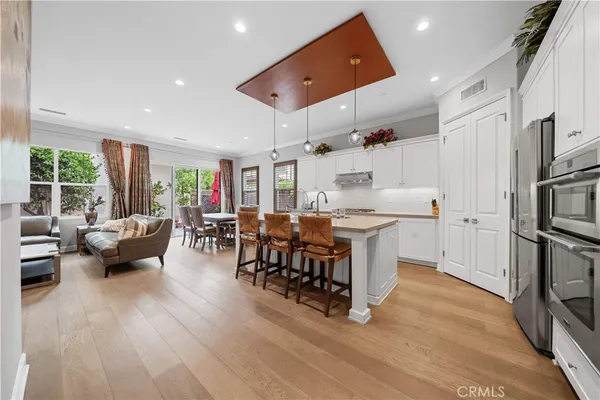 a large white kitchen with stainless steel appliances kitchen island granite countertop a large window and white cabinets