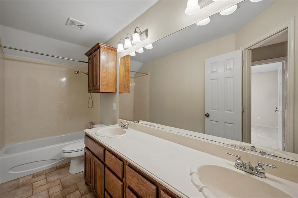 5607 Ranger Drive Rockwall, TX 75032 - Photo 33 of 40 Bathroom vanity with dual sinks, wood-finish cabinetry, and a full-width mirror