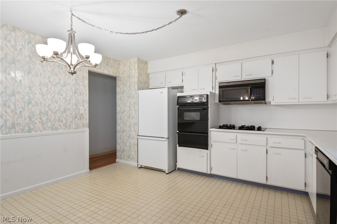 28879 Ridge Road Wickliffe, OH 44092 - Photo 10 of 34 Kitchen with a chandelier, pendant lighting, light tile flooring, black appliances, and white cabinetry