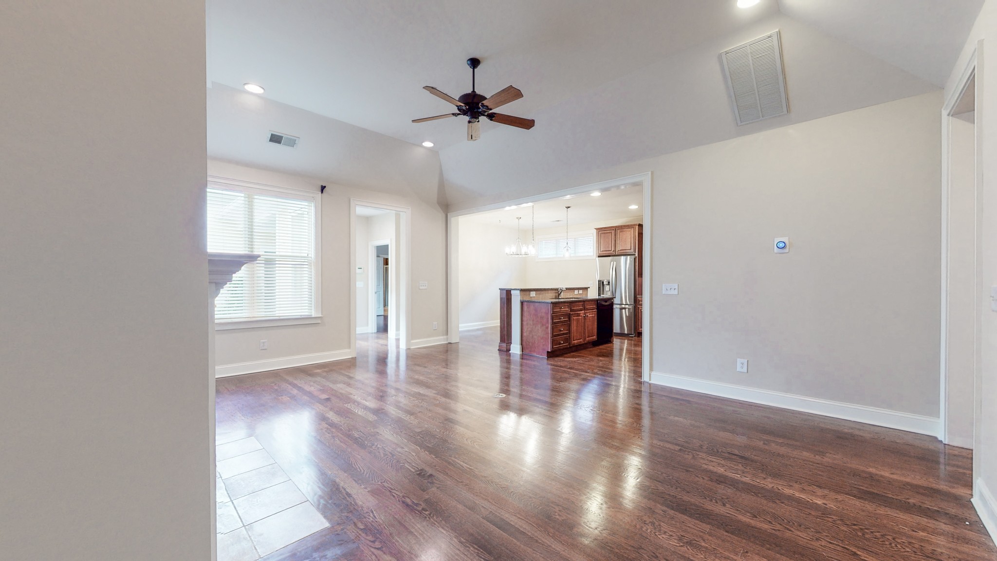 718 Pearre Springs Way Franklin, TN 37064 - Photo 4 of 46 an empty room with wooden floor ceiling fan and kitchen view