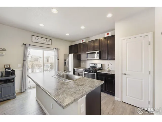 a kitchen with kitchen island granite countertop stainless steel appliances a sink stove refrigerator and cabinets