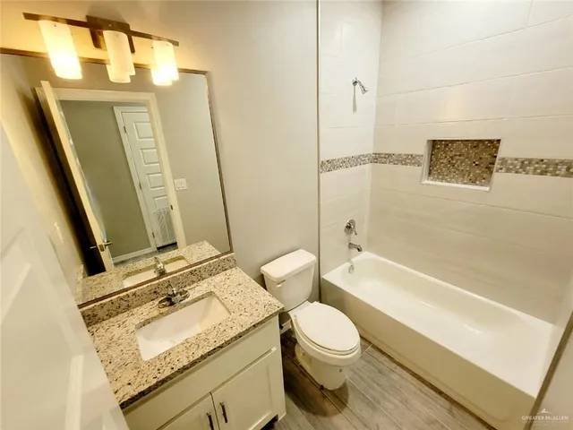 a bathroom with a granite countertop sink and a toilet
