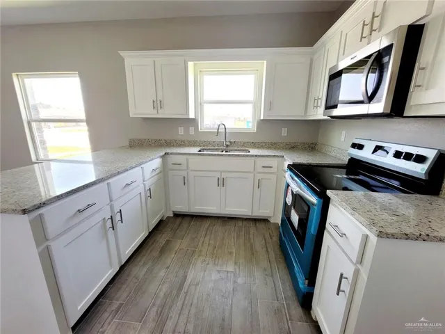 a kitchen with appliances cabinets a sink and a window