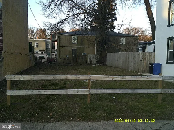 a view of backyard with wooden fence and large trees