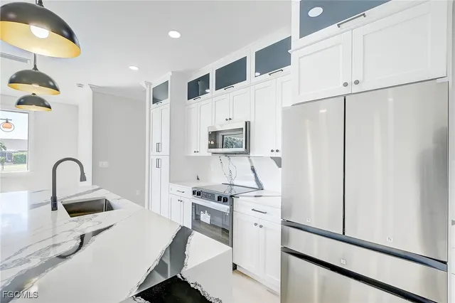 a kitchen with stainless steel appliances a refrigerator stove and white cabinets