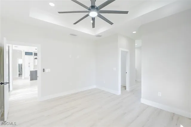 an empty room with wooden floor and ceiling fan