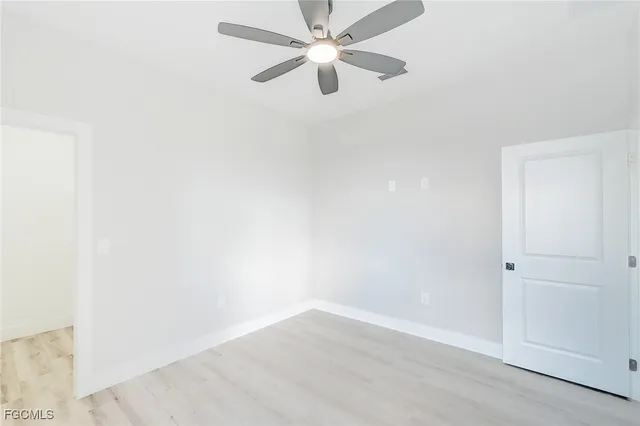 an empty room with a window and a ceiling fan