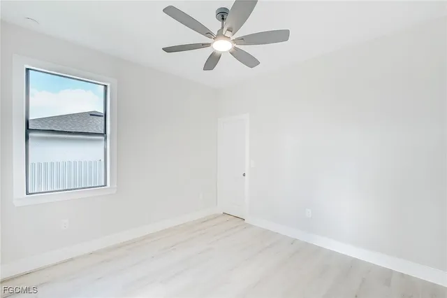 an empty room with a window and a fan