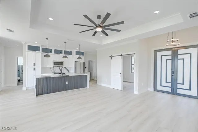 a living room with stainless steel appliances kitchen island hardwood floor and a window