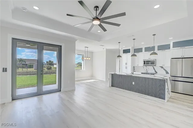 a kitchen with stainless steel appliances granite countertop a refrigerator a sink a stove and a wooden floors