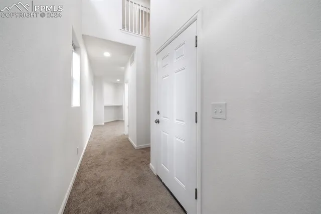 a view of a hallway with wooden floor and a bathroom