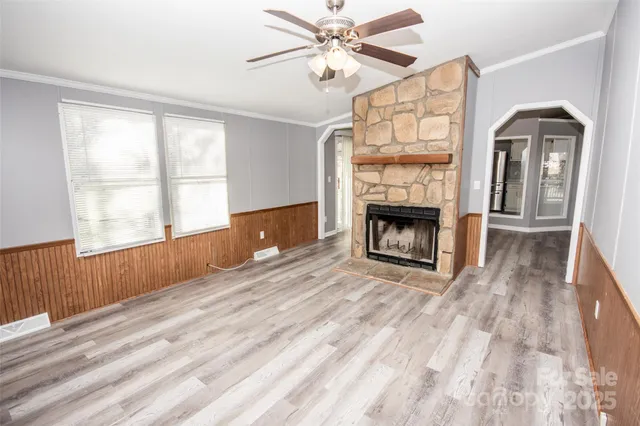 a view of an empty room with wooden floor fireplace and a window