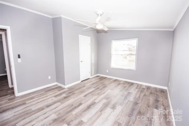 a view of an empty room with window and wooden floor