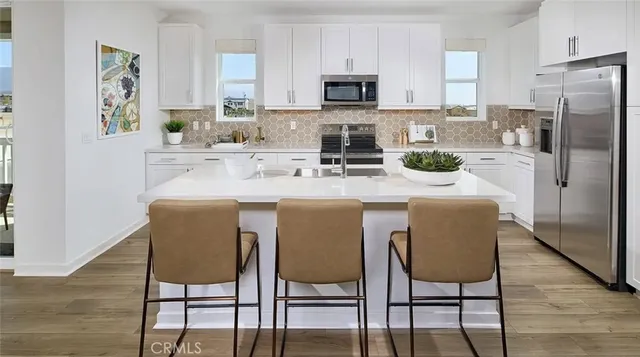 a kitchen with stainless steel appliances granite countertop a table chairs microwave and refrigerator