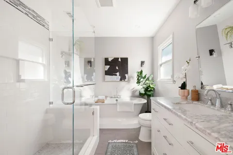 a bathroom with a granite countertop sink a toilet and a shower