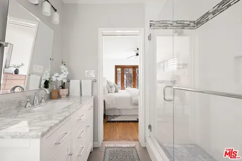 a bathroom with a granite countertop sink a mirror and shower