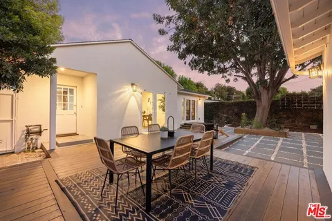 a view of a patio with table and chairs with wooden floor and fence