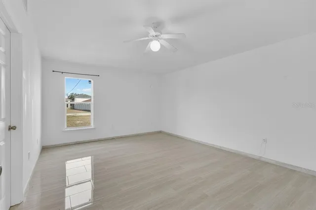 an empty room with a window and a ceiling fan
