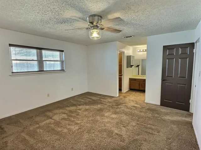 an empty room with chandelier fan and windows