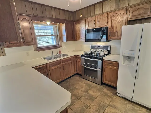 a kitchen with stainless steel appliances granite countertop a sink stove microwave and refrigerator