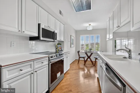 a kitchen with stainless steel appliances granite countertop sink stove top oven and cabinets