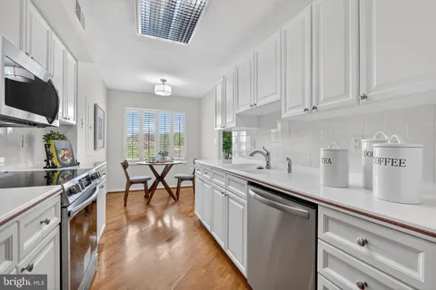a kitchen with stainless steel appliances a sink a stove top oven a refrigerator a sink a counter space and cabinets