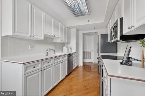 a kitchen with white cabinets and sink