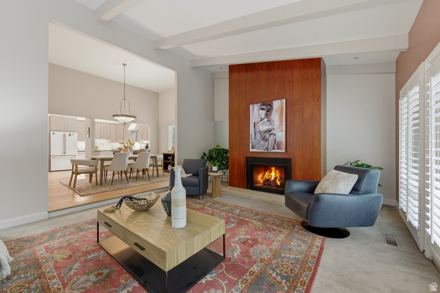 3674 Oak Rim Way Salt Lake City, UT 84109 - Photo 8 of 47 Living area featuring a floor-to-ceiling wood-paneled fireplace surround, white plantation shutters, exposed ceiling beams, and an open concept layout