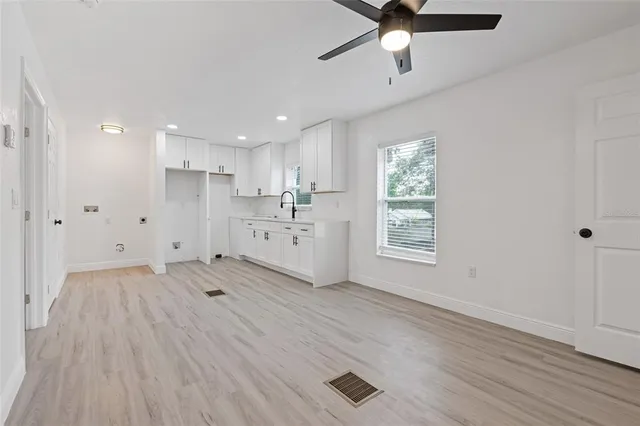 a kitchen with white cabinets and window