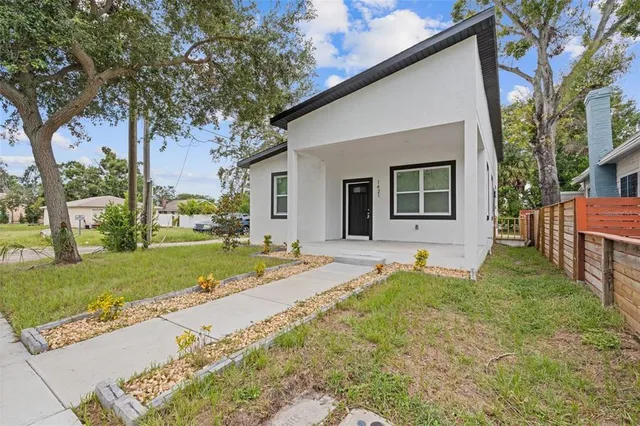 a view of a house with a yard and large tree