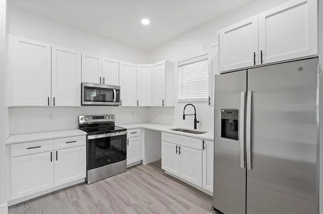 a kitchen with white cabinets and stainless steel appliances