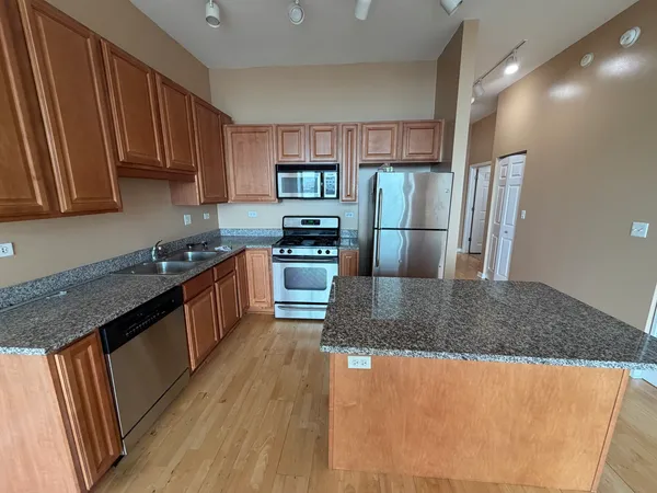 a kitchen with stainless steel appliances granite countertop a refrigerator a stove top oven a sink and dishwasher