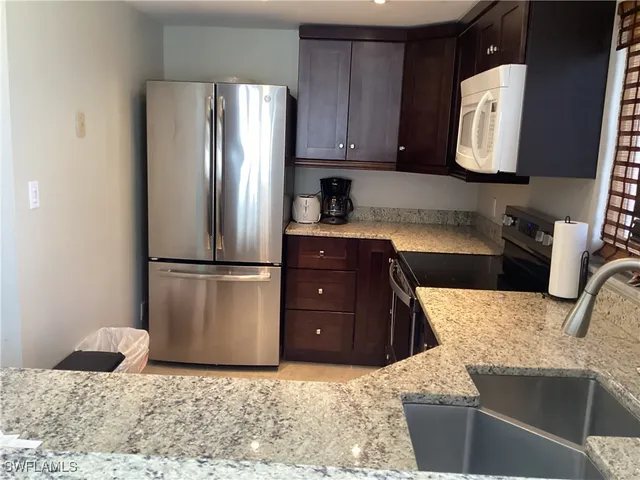 a kitchen with stainless steel appliances granite countertop a refrigerator sink and stove