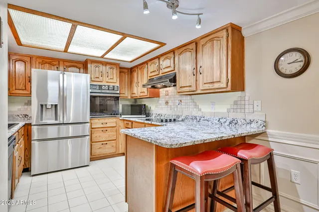 a kitchen with stainless steel appliances granite countertop a refrigerator and a stove top oven